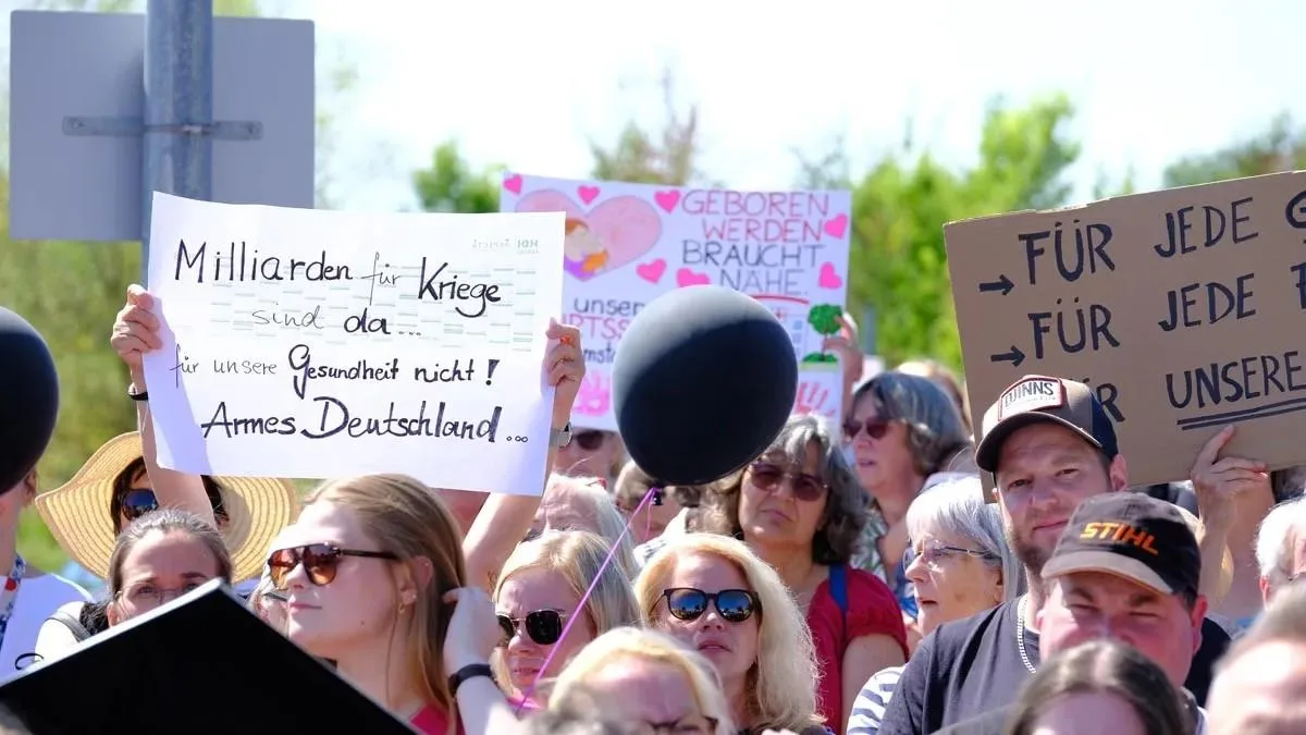 Demonstrierende mit Schildern, darunter eines mit der Aufschrift „Milliarden für Kriege – Gesundheit nicht?“.